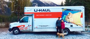Tillman Scholar, woman and dog outside of U-Haul truck in snowy forest.