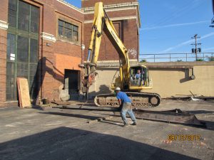 Excavator opening up exterior wall to U-Haul NBC-Nabisco Detroit building showroom